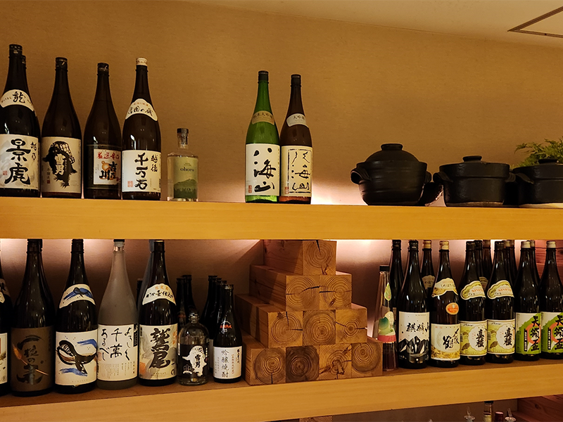 越乃景虎や八海山などの日本酒と釜が並ぶつみきの棚